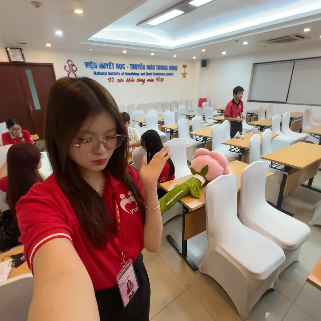 Phương Vy trong áo tình nguyện màu đỏ tại Viện Huyết học