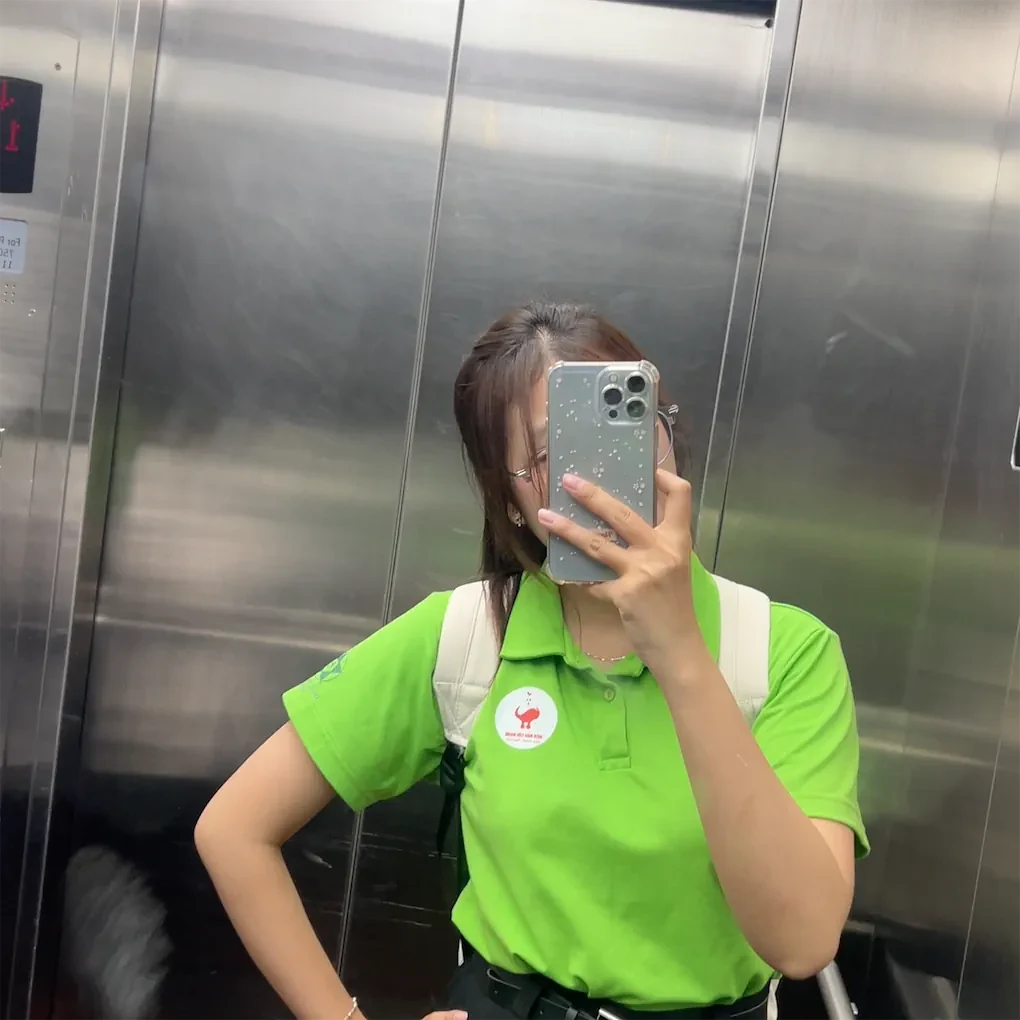 Phương Vy chụp ảnh qua gương trong áo tình nguyện màu xanh lá