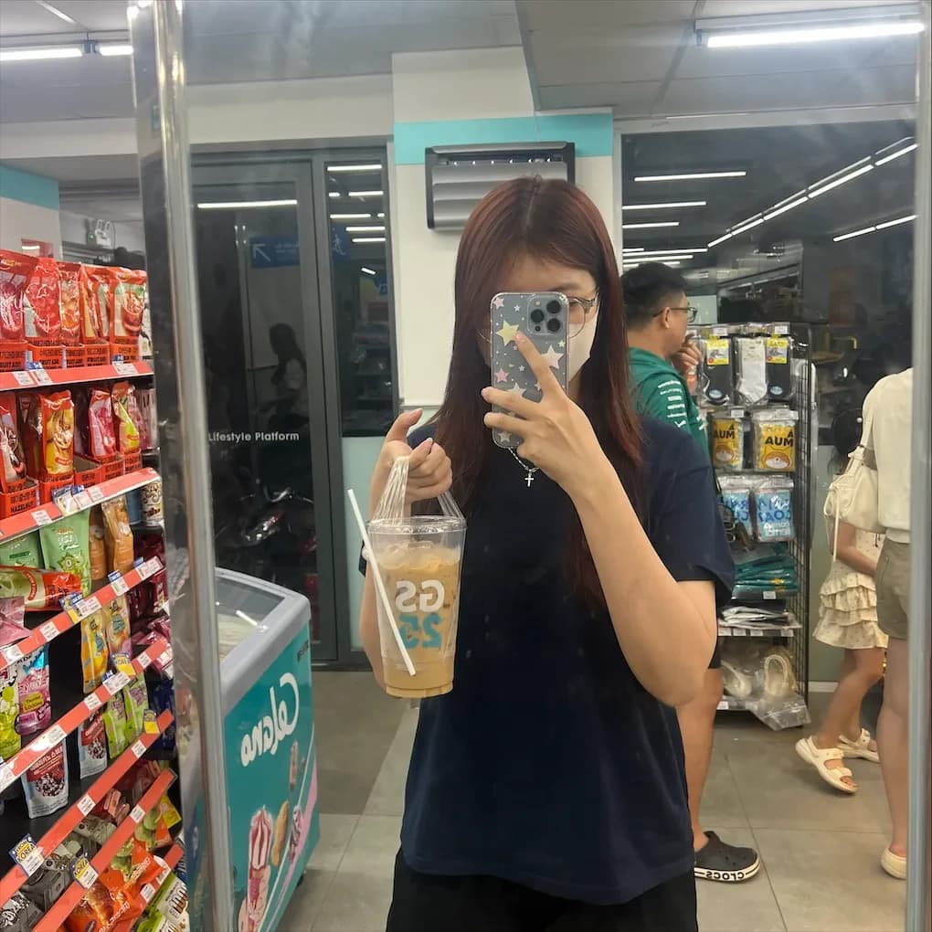 Phương Vy chụp ảnh qua gương tại cửa hàng tiện lợi